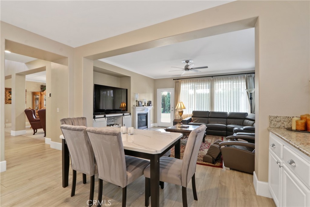 Open-plan dining and living room with a leather sectional, fireplace, and large curtained windows.