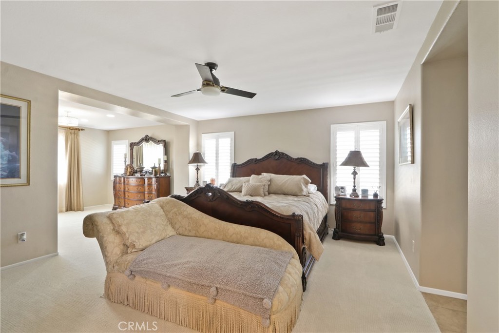 Furnished bedroom with a carved wood bed, matching nightstands, and a chaise lounge.
