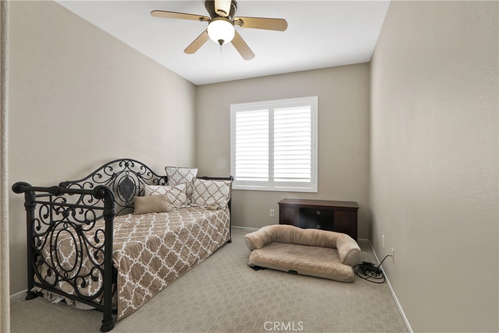 Bedroom with a wrought-iron daybed, plantation shutters, and a cushioned pet bed.