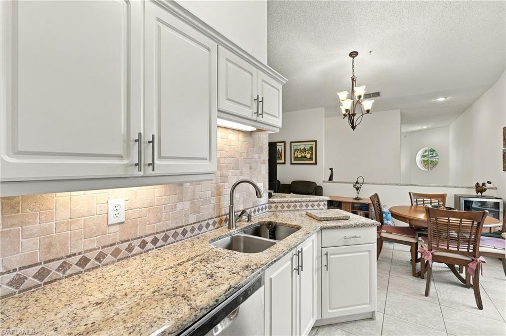 Kitchen with white cabinets and granite counters opening to a dining area with a round table.