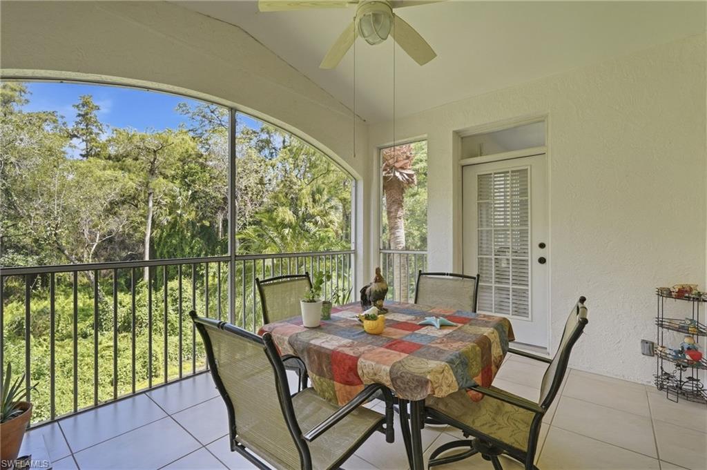 Screened lanai with a dining set and a wide arched view of trees and palms.