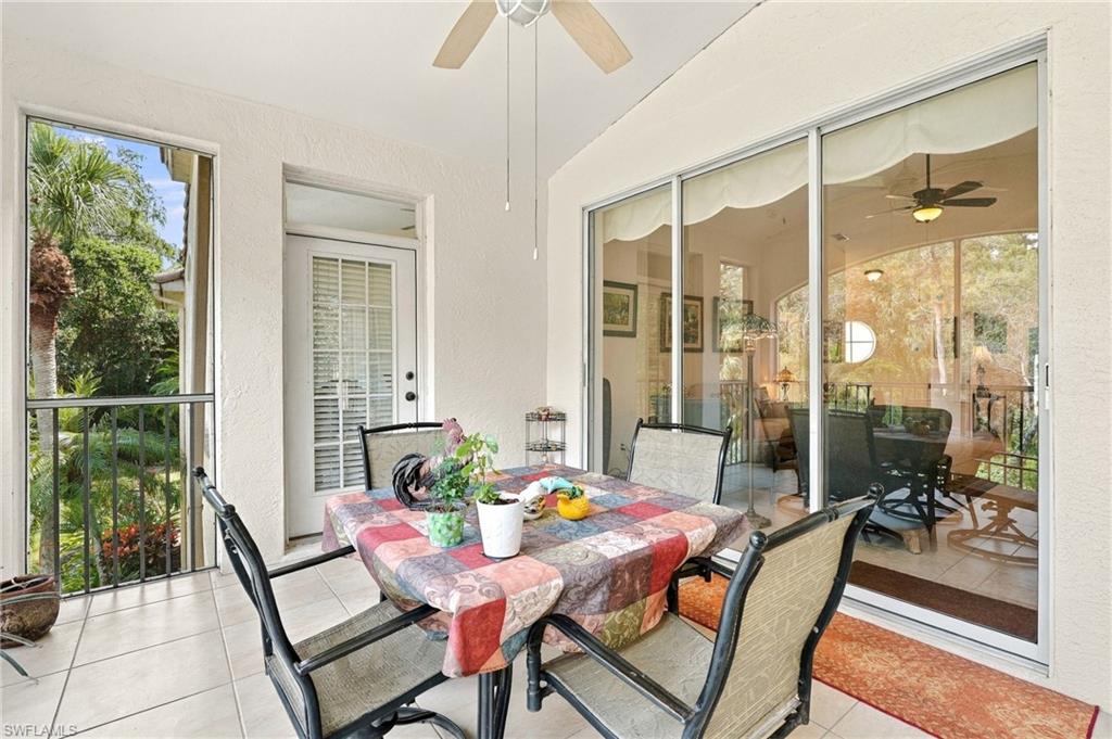 Covered lanai with a colorful dining table, sliding glass doors, and tropical garden views.