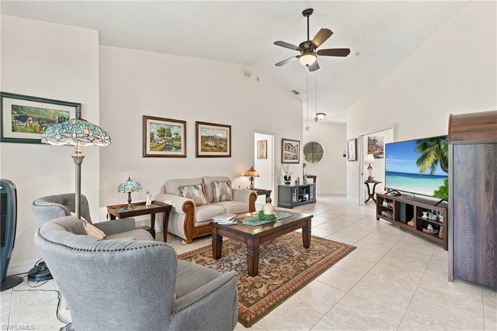 Furnished living room with a ceiling fan, tiled floors, and a television showing a tropical beach.