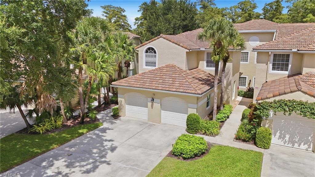 Two-story home with a double garage, terracotta roof tiles, palms, and a landscaped driveway.