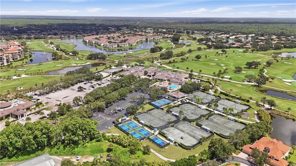 Aerial view of a golf course community with tennis courts, a pool, and lakes.