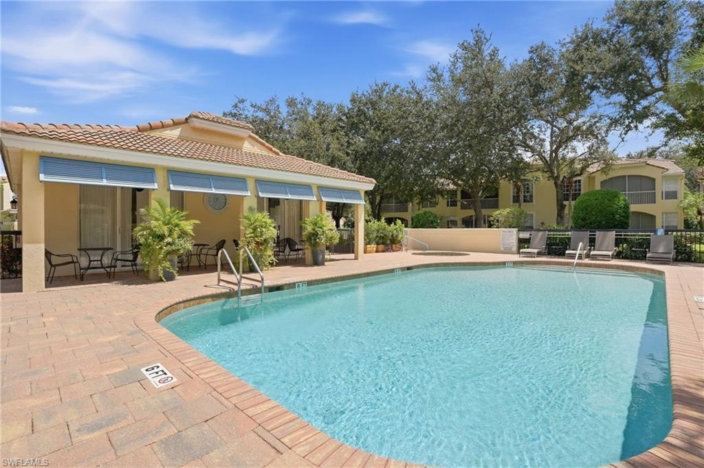 Community swimming pool beside a covered cabana, with lounge chairs and mature trees.