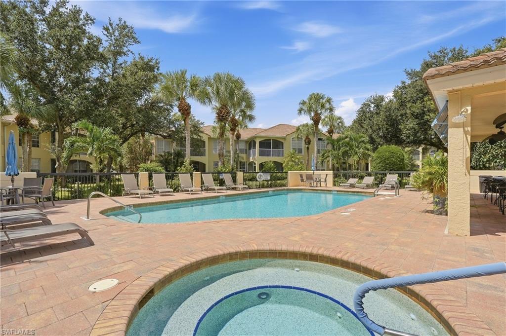 Community pool and circular spa with lounge chairs and palm trees.