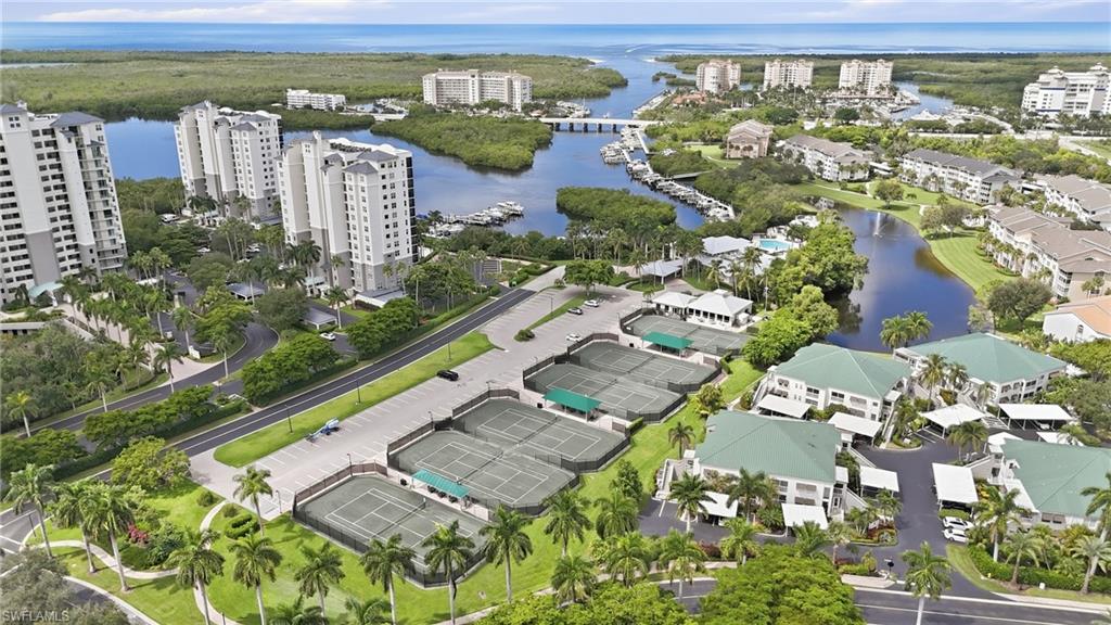 Aerial view of a coastal condominium community with tennis courts and waterways leading to the Gulf.