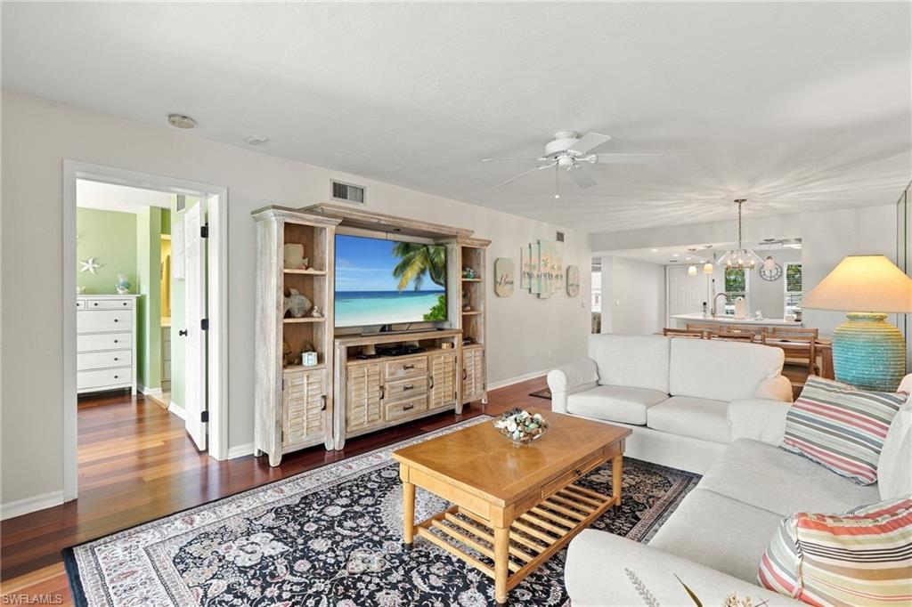 Living room with white sectional, patterned rug, wooden coffee table, and entertainment center.