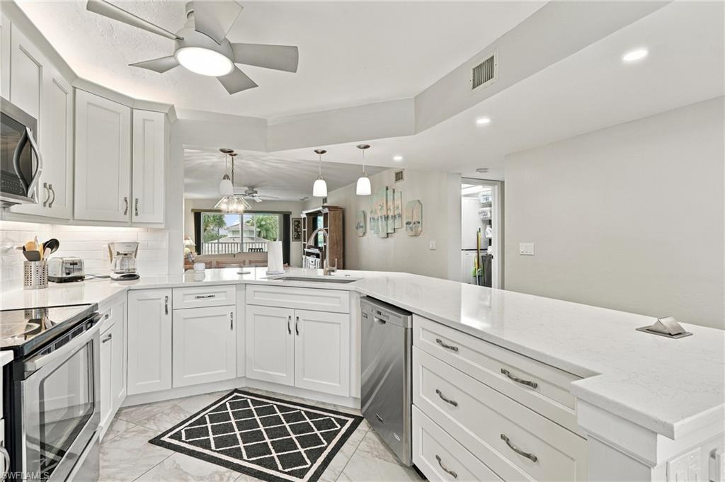 Updated white kitchen with a long stone island, stainless steel appliances, and a geometric floor mat.
