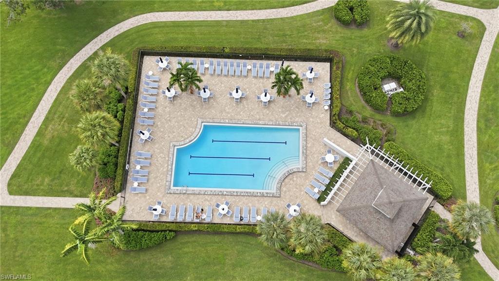 Aerial view of a lap pool surrounded by lounge chairs, landscaped grounds, and a covered pavilion.