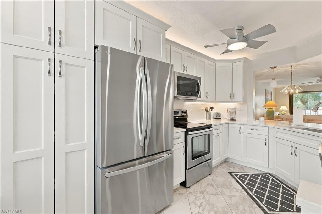 White kitchen with stainless-steel appliances, paneled cabinets, and a black geometric floor runner.