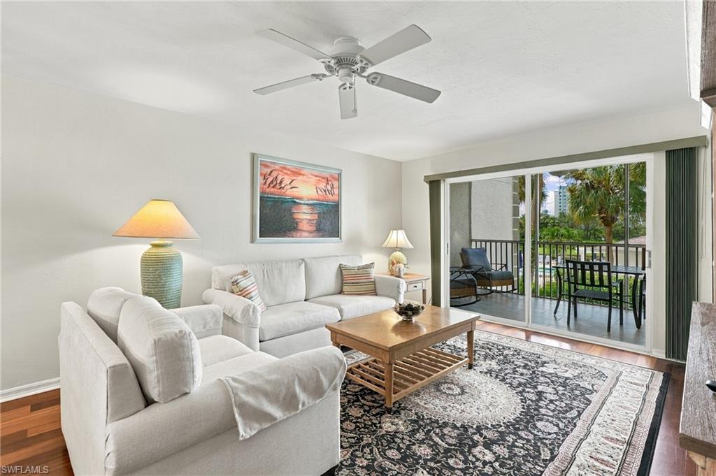 Furnished living room with white sofas and a sliding door opening to a balcony.
