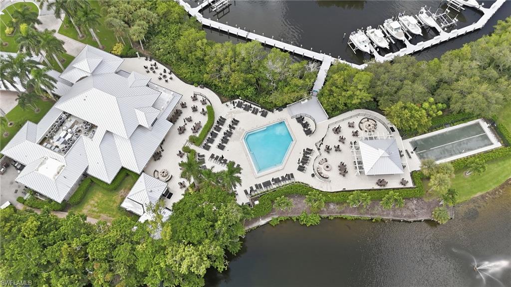 Aerial view of a waterfront clubhouse and pool, with landscaped terraces, docks, and boats.
