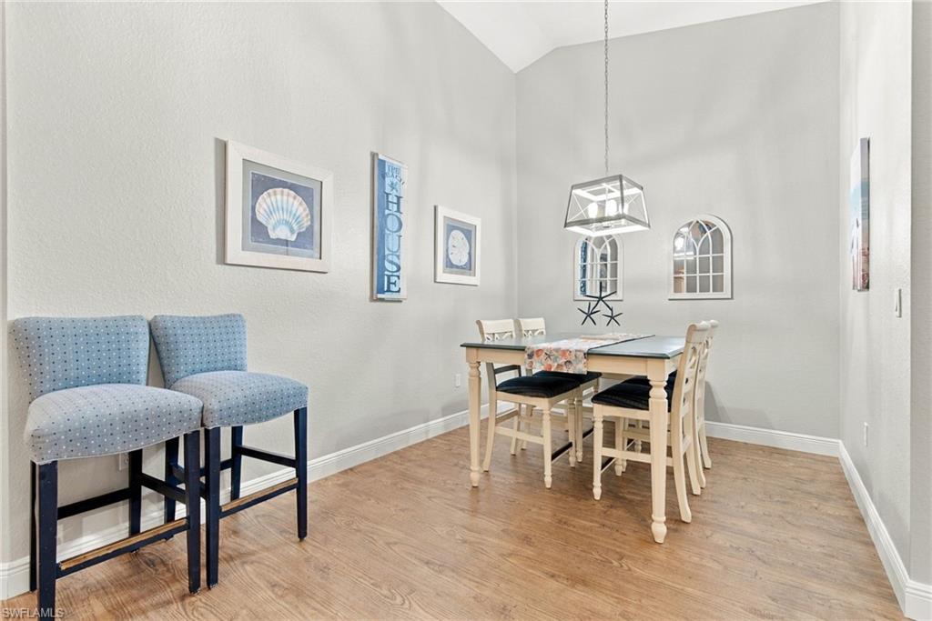 Dining area with a light wood table, blue bar stools, and coastal wall art.