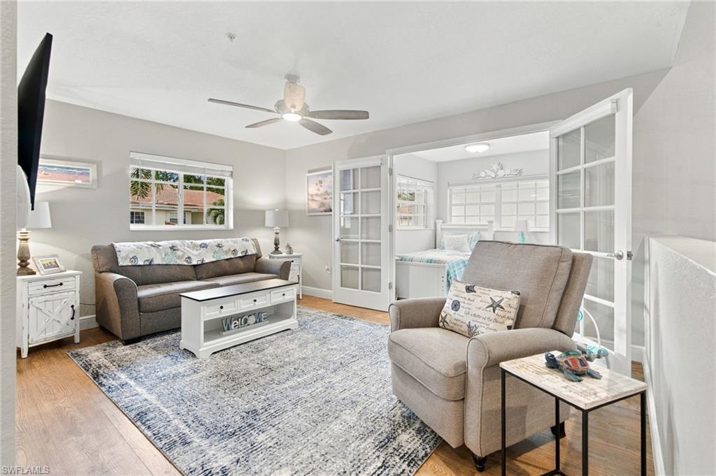 Furnished living room with a gray sofa, recliner, patterned rug, and French doors to a bedroom.