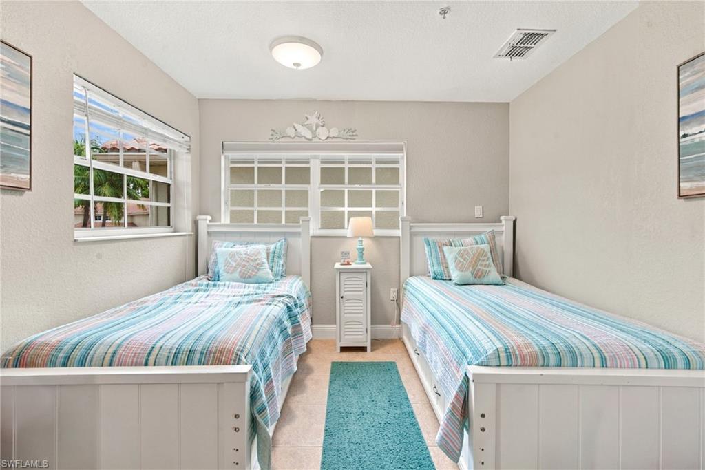 Bedroom with two twin beds, striped pastel bedding, and a turquoise lamp between them.