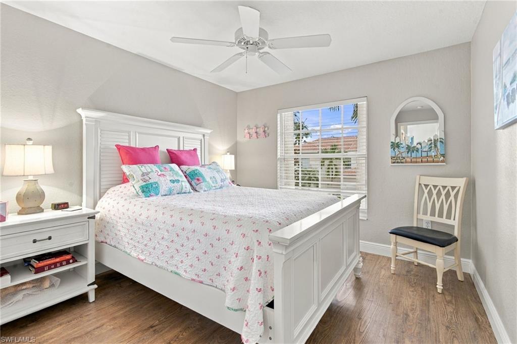 Bedroom with a white paneled bed, colorful pillows, and a window with blinds.