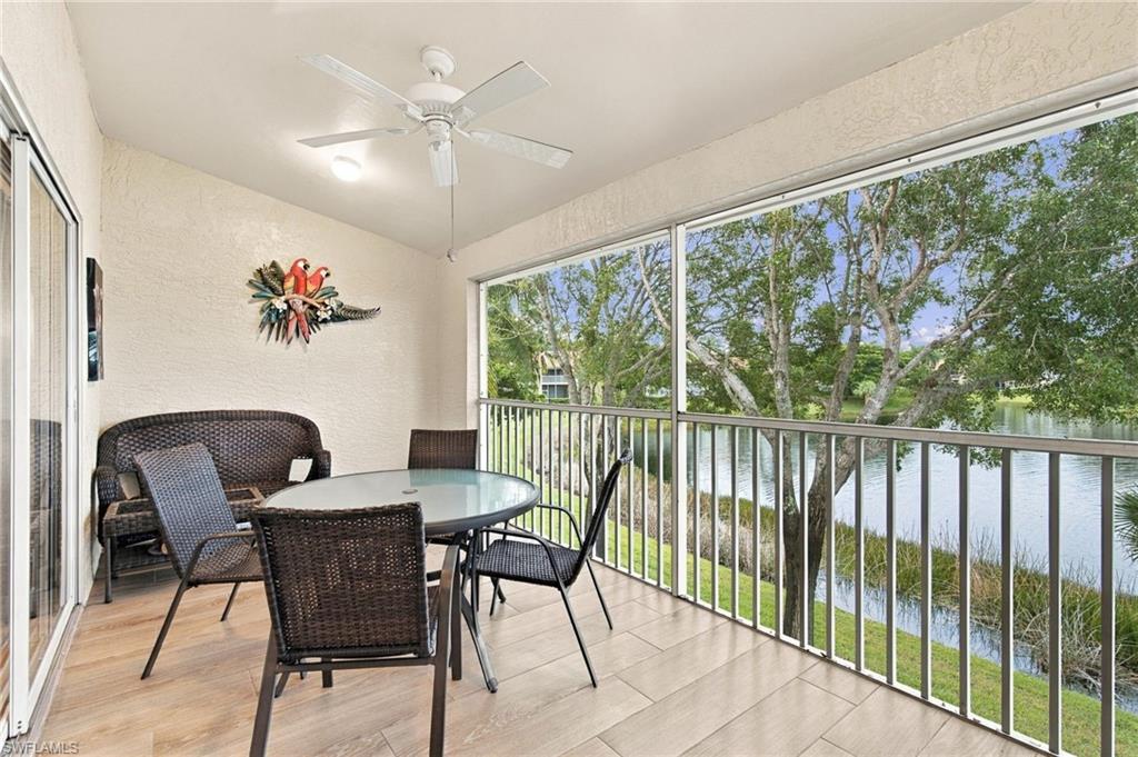Screened lanai with wicker dining furniture overlooking a lake and leafy trees.