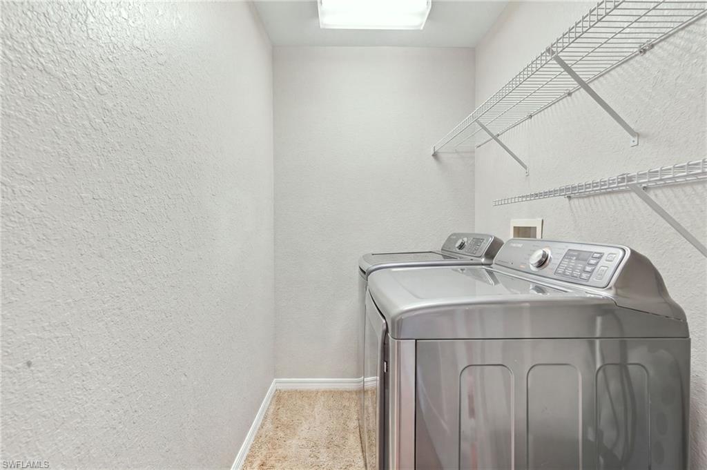 Laundry room with two silver top-loading appliances and wire shelving.