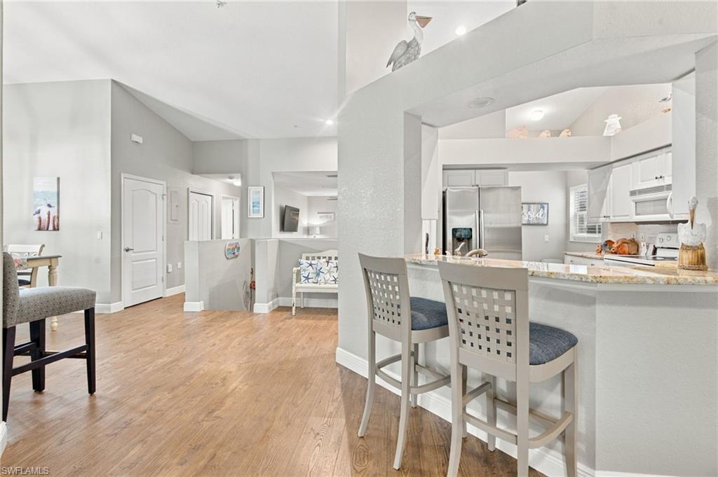 Open-plan condo kitchen with granite breakfast bar, stainless steel appliances, and adjoining living and dining areas.
