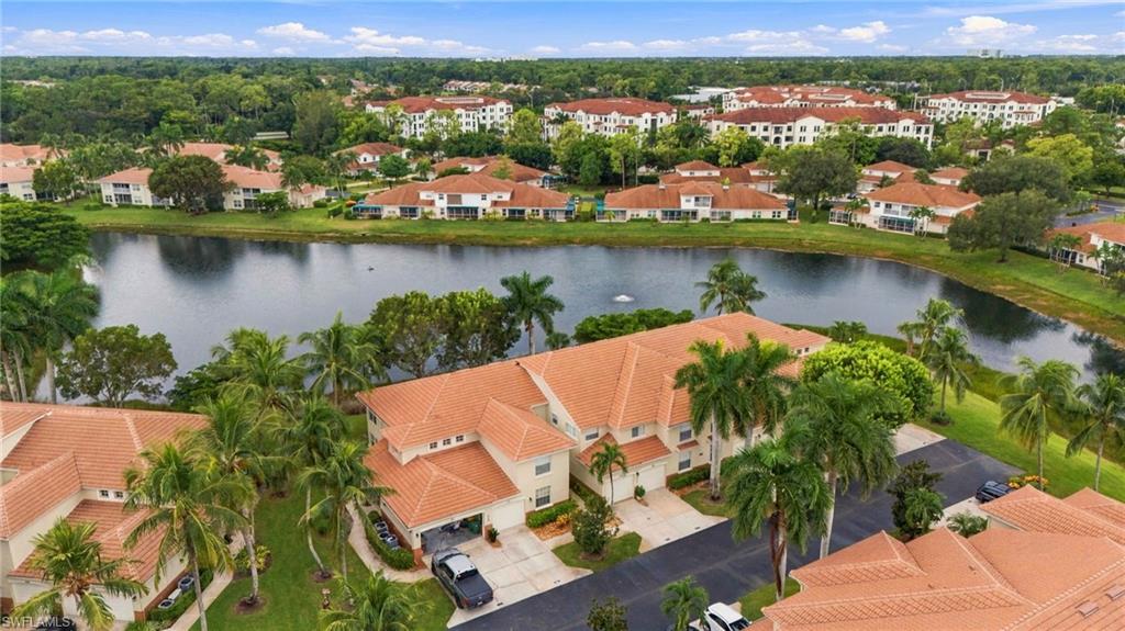 Aerial view of terracotta-roofed condominiums, palms, and a lake in Naples.