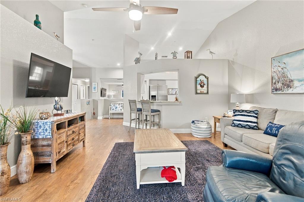 Open-plan living room with vaulted ceilings, gray sectional, blue chair, and breakfast bar