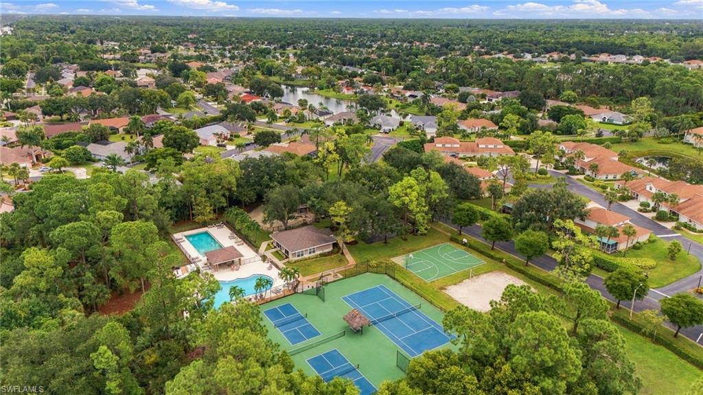 Aerial view of a leafy Naples neighborhood with tennis courts and swimming pools.