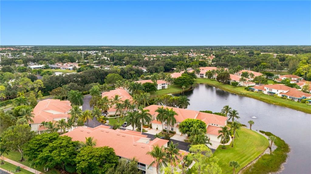 Aerial view of a lakeside community with terracotta-roofed buildings and palm trees.