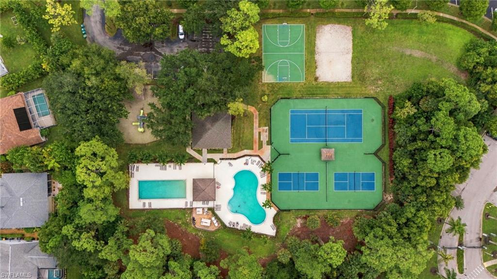 Aerial view of community pool and tennis courts amid lush landscaping.