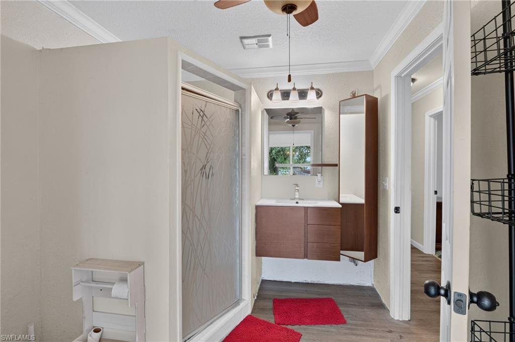 Bathroom with a glass shower, floating wood vanity, and red bath mats.