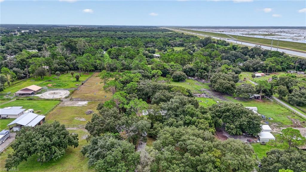 Aerial view of wooded acreage with scattered outbuildings and open grassy areas.