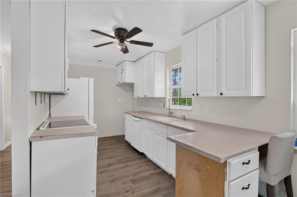 Kitchen with white cabinets, long peninsula, and a window above the sink.