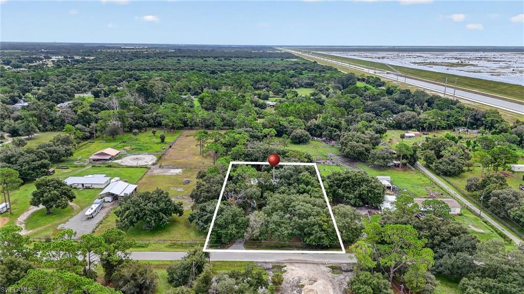 Aerial view of a tree-covered parcel outlined beside a road, with a canal visible in the distance.