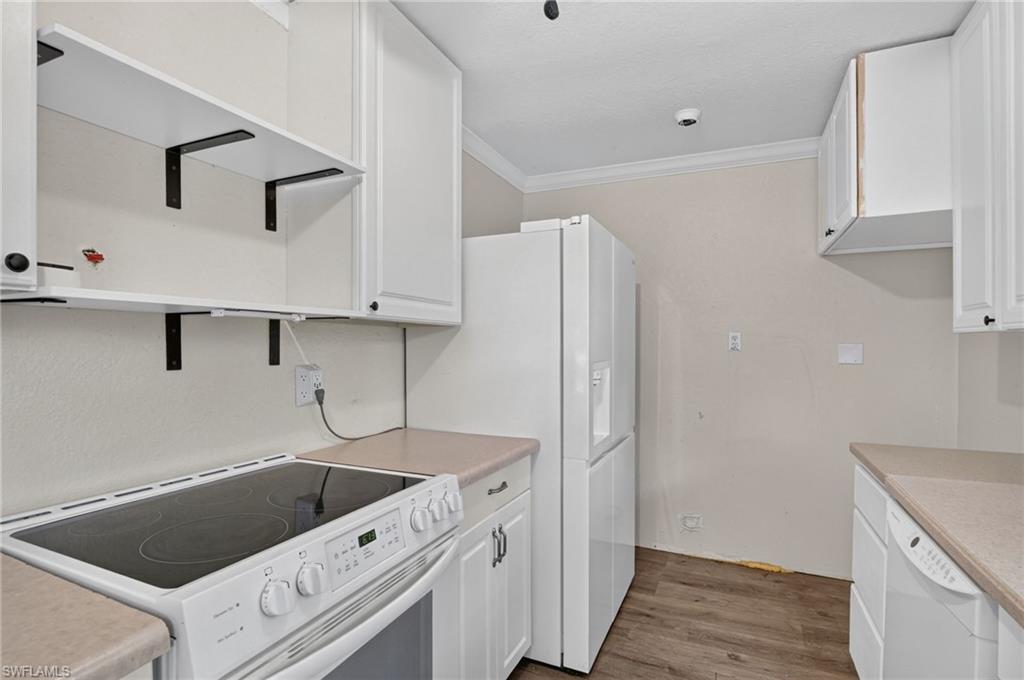 Kitchen with white cabinetry, open shelving, and electric appliances.