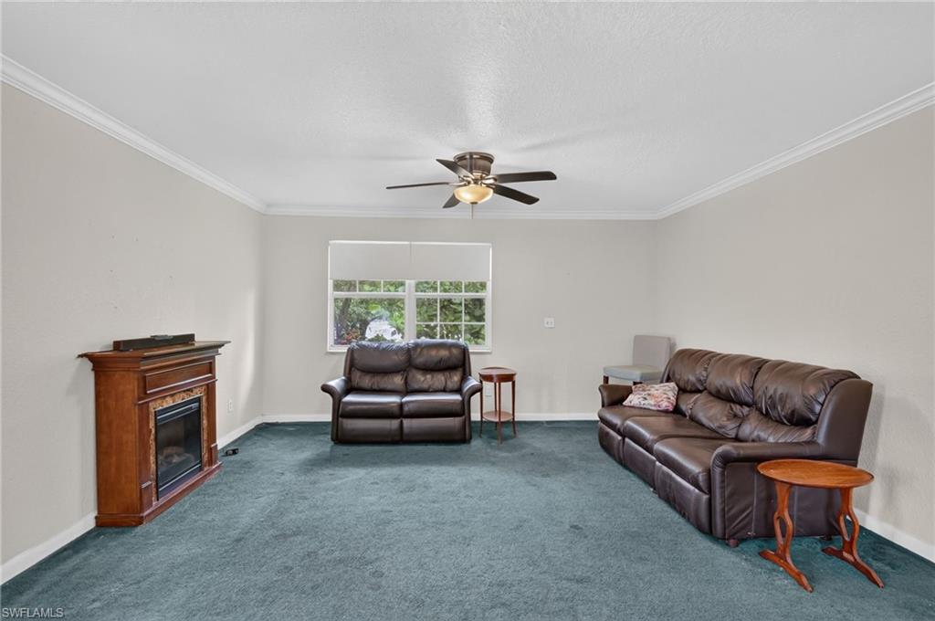 Living room with teal carpet, brown leather sofas, and a wooden fireplace cabinet.