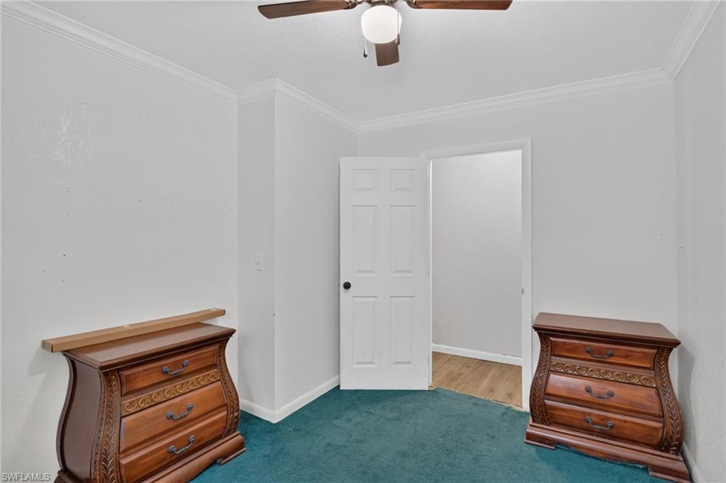 Bedroom with teal carpet, ornate wooden dressers, and an open door.