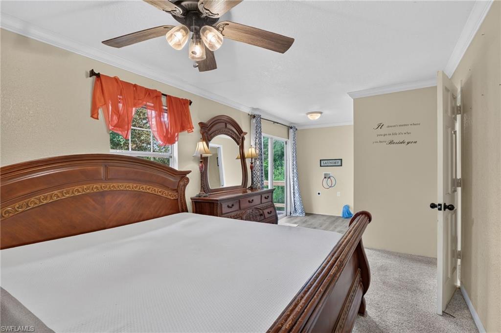 Bedroom with a carved wooden bed, matching dresser and mirror, ceiling fan, and sliding glass door.