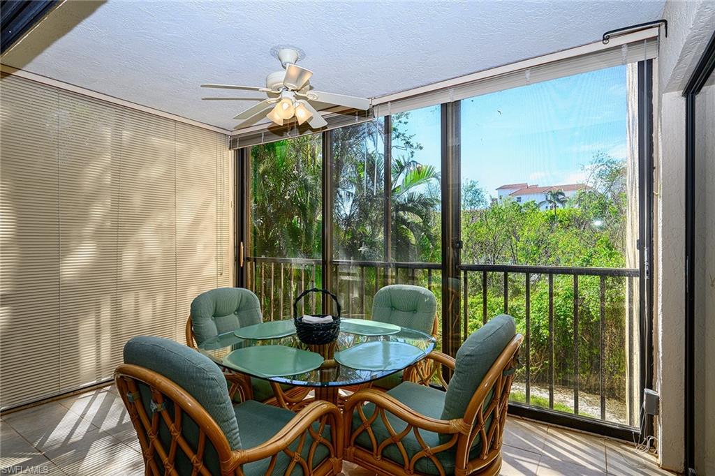 Enclosed lanai with wicker dining chairs, sliding glass doors, and tropical greenery outside.