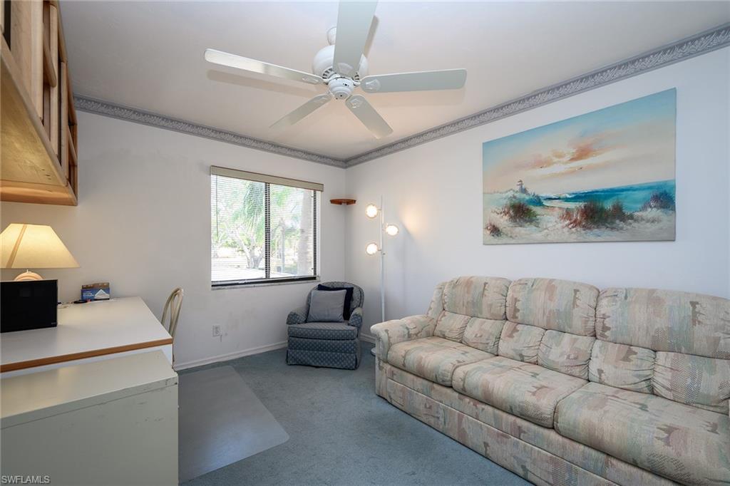 Furnished living room with a patterned sofa, blue armchair, and ocean-themed wall art.