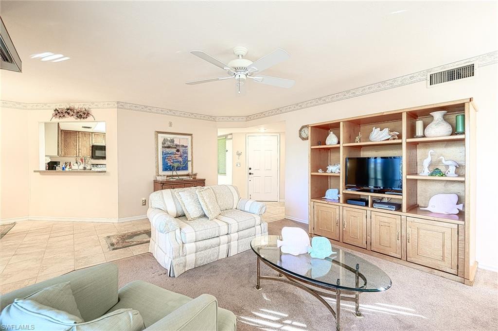 Living room with built-in wooden entertainment shelving, a television, and a glass coffee table.