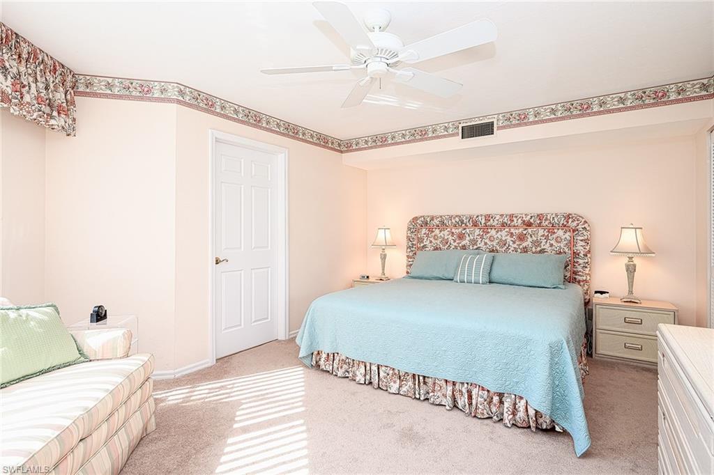 Bedroom with a pale blue bed, floral trim, ceiling fan, and striped armchair.