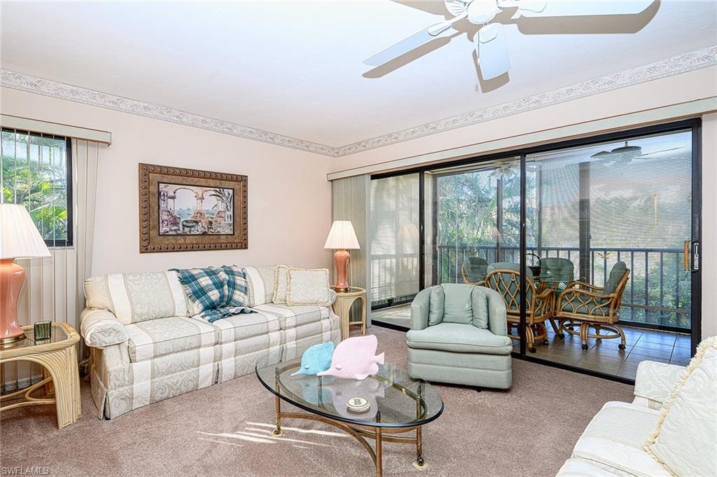 Living room with cream sofas, a glass coffee table, and sliding doors to a screened balcony.