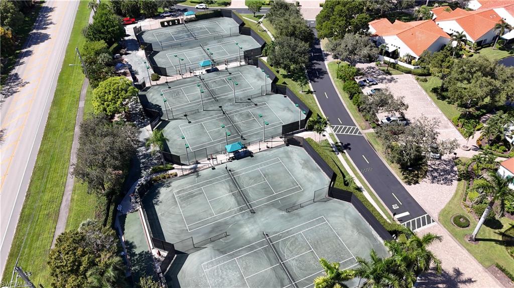 Aerial view of multiple tennis courts beside landscaped homes and neighborhood roads.