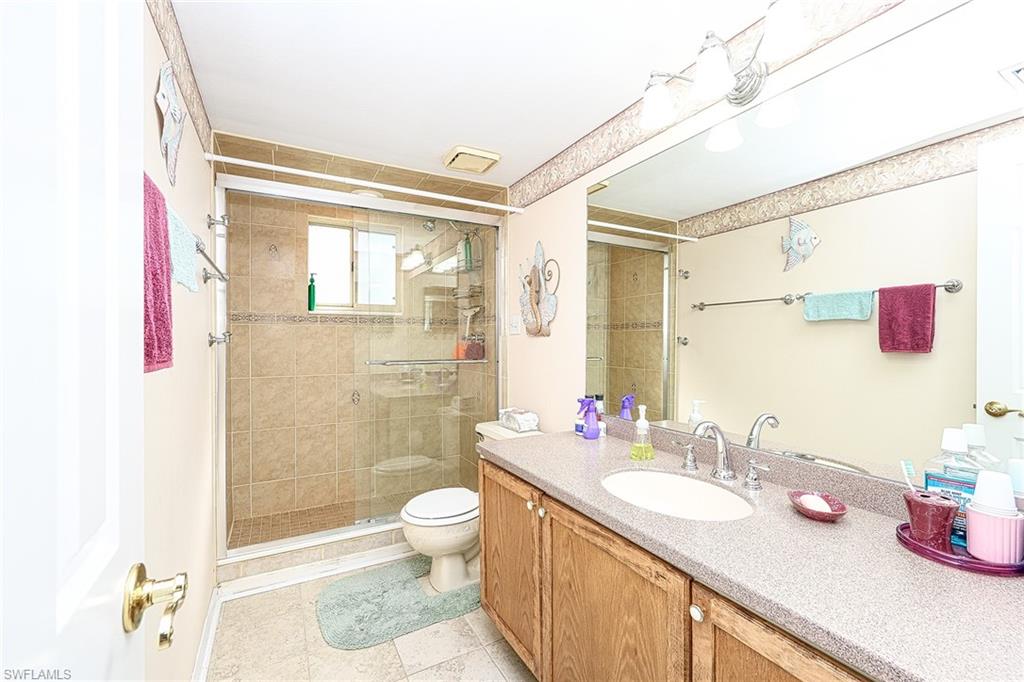 Bathroom with a glass-enclosed tile shower and long wood vanity.