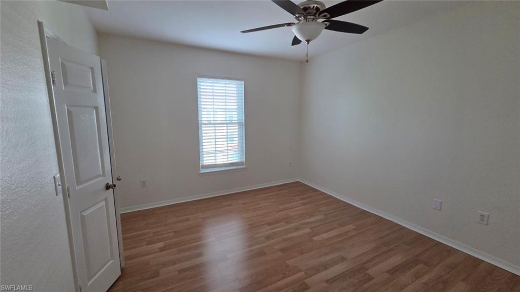 Unfurnished room with wood flooring, a window with blinds, and a ceiling fan.