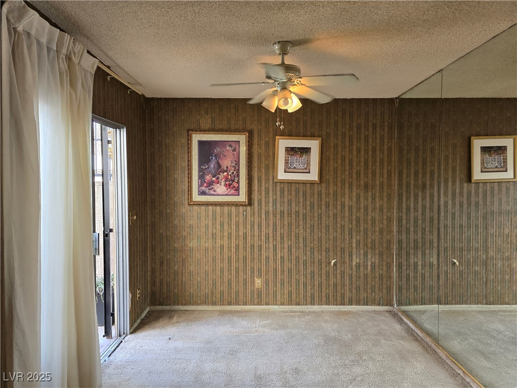 Unfurnished bedroom with a mirrored wall, ceiling fan, and open sliding glass door.