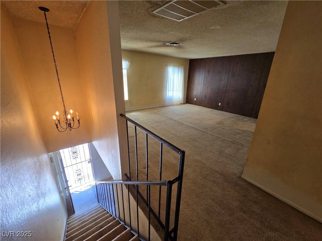Carpeted upstairs living area with a dark wood-paneled wall overlooking the staircase.