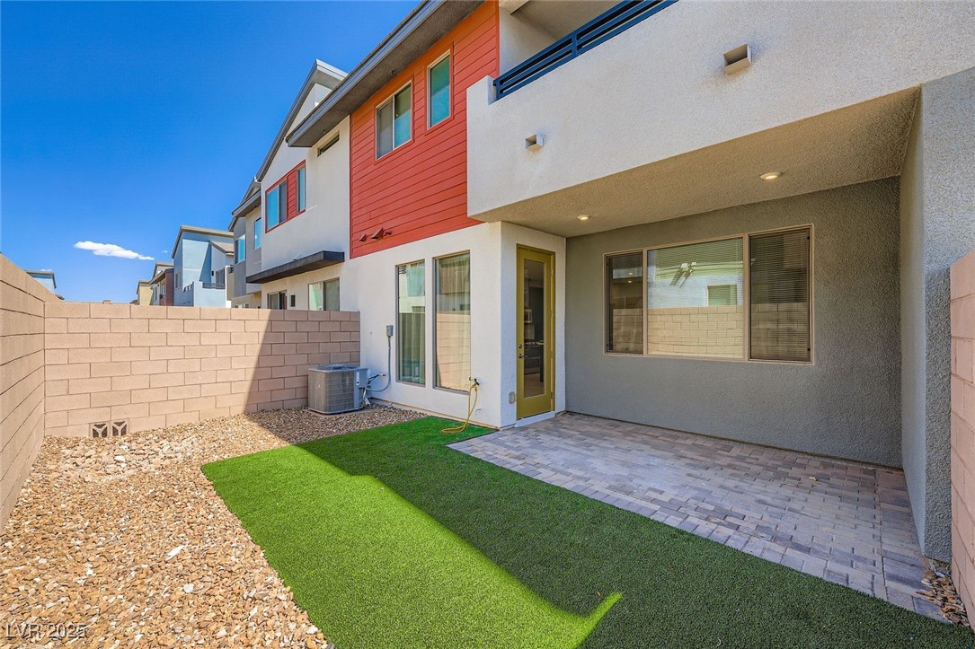Rear patio with artificial turf, pavers, and gravel landscaping.