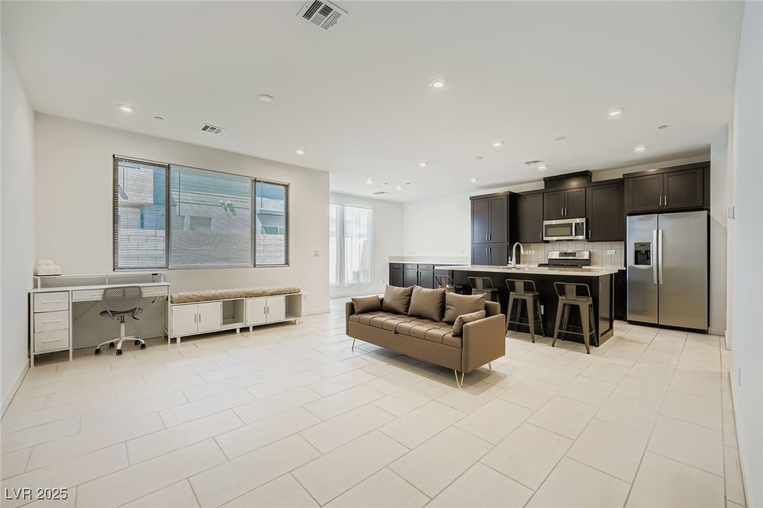 Open-plan kitchen and living area with dark cabinets, a large island, and a sofa.